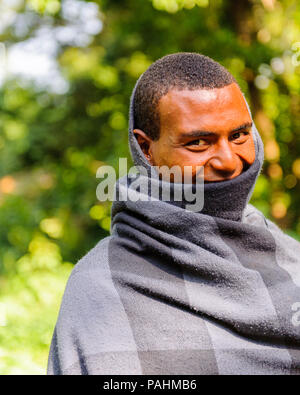 OMO VALLEY, ETHIOPIA - SEP 20, 2011: Portrait of an unidentified Ethiopian man covered with black and blue blanket Ethiopia, Sep.20, 2011. People in E Stock Photo