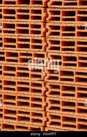 Stacked orange bricks. Construction industry. Building pieces. Vertical Stock Photo