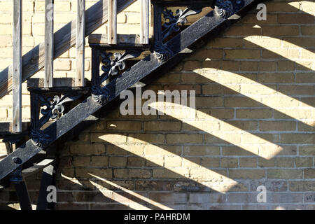 Close up view of an urban fire escape staircase in front of an old tan colored brick wall building Stock Photo