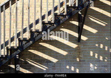 Close up view of an urban fire escape staircase in front of an old tan colored brick wall building Stock Photo