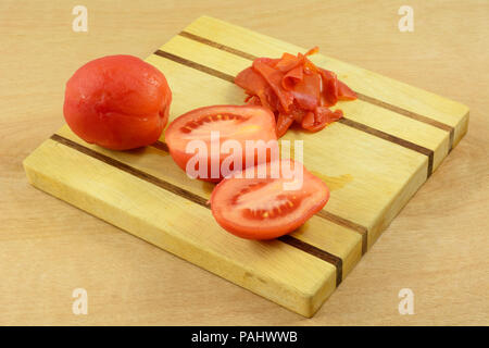 Peeled tomatoes after quick one minute boiling to retain raw texture and flavor with peel on wooden cutting board Stock Photo