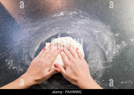 Woman preparing pizza dough on black granite table Stock Photo