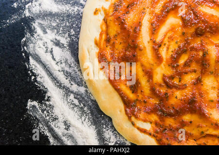 Preparing pizza, close-up of pizza dough with tomato sauce. Stock Photo