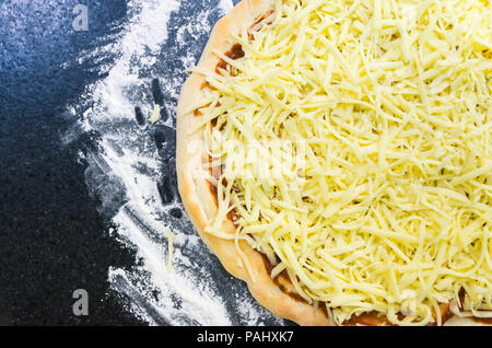 Preparing pizza, close-up of pizza dough with tomato sauce and mozzarella cheese. Stock Photo