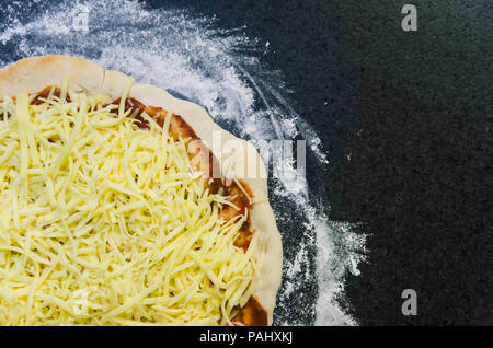 Preparing pizza, close-up of pizza dough with tomato sauce and mozzarella cheese. Stock Photo