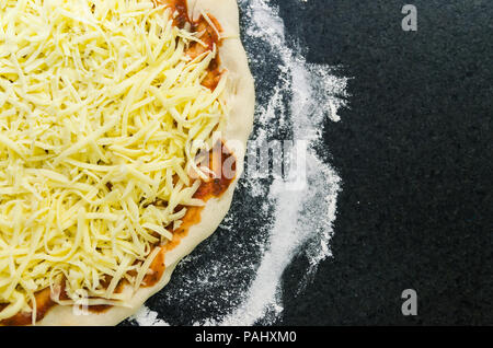 Preparing pizza, close-up of pizza dough with tomato sauce and mozzarella cheese. Stock Photo