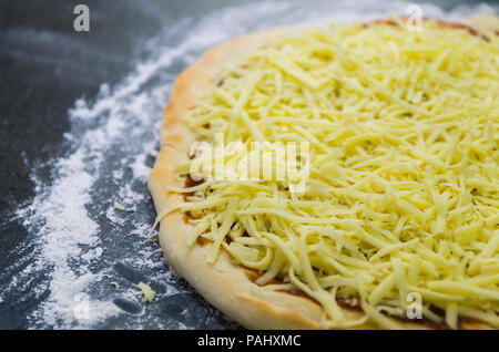 Preparing pizza, close-up of pizza dough with tomato sauce and mozzarella cheese. Stock Photo