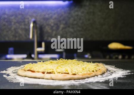 Preparing pizza, close-up of pizza dough with tomato sauce and mozzarella cheese. Stock Photo