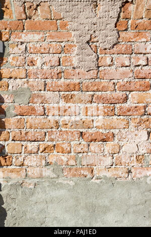 Vertical image of a very distressed old light brown brick wall showing a large amount of exposed mortar Stock Photo