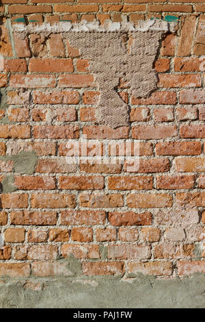 Vertical image of a very distressed old light brown brick wall showing a large amount of exposed mortar Stock Photo