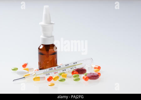 Thermometer, pills, nasal spray on white background. Cold and flu concept Stock Photo