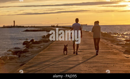 At sunset people with dog walking on the mole. Stock Photo