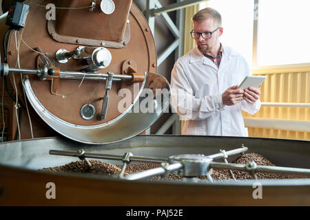 Modern Worker Roasting Coffee at Factory Stock Photo