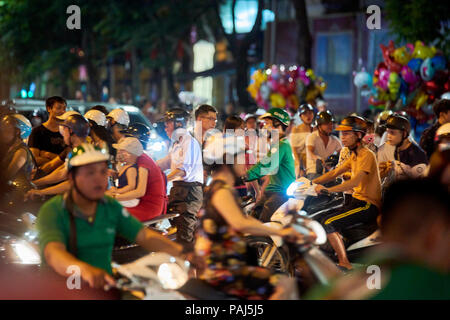 Motion blurred night shot of mopeds in busy street in Hanoi, Vietnam. The seemingly chaotic traffic scares tourists but is commonplace for locals. Stock Photo