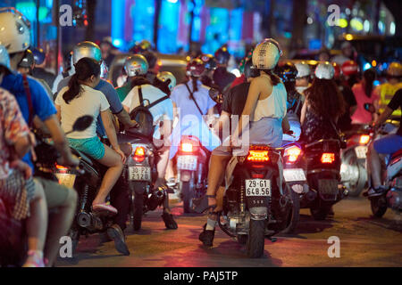 Night shot of mopeds from behind in busy street in Hanoi, Vietnam. The seemingly chaotic traffic scares tourists but is commonplace for locals. Stock Photo