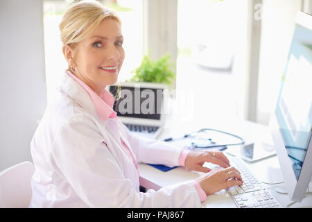 Smiling senior female research physician using computer and laptop ...
