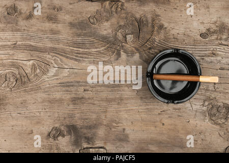 Cigar in an ashtray on a old wooden desk, with a place for your text. View from above Stock Photo