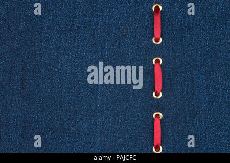 Red silk ribbon is inserted in a dark denim fabric. With place for your text. View from above. Stock Photo