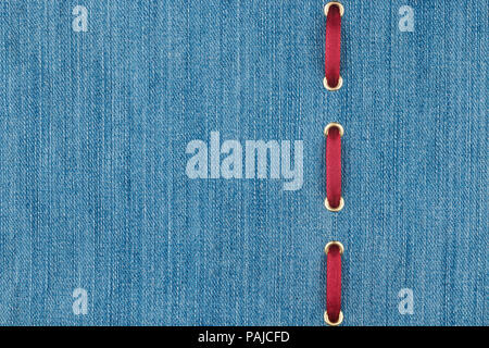 Red silk ribbon is inserted in a light denim fabric. With place for your text. View from above. Stock Photo