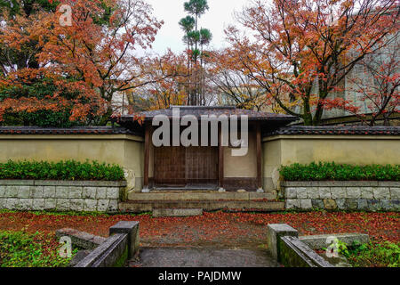 Kyoto, Japan - Nov 19, 2016. Wooden gate of ancient palace with maple trees at autumn in rainy day. Stock Photo