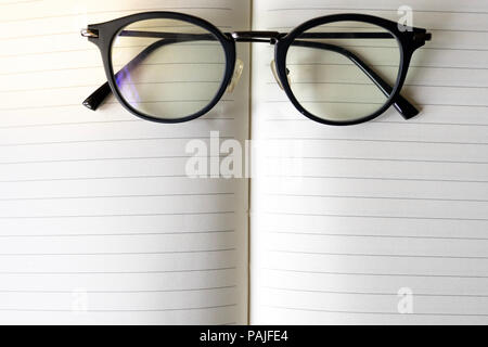 close up modern glasses on blurred opened book with copy space Stock Photo
