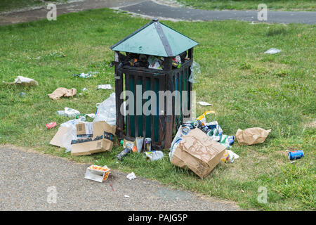 A municipal rubbish bin overflowing with litter left by the public on a summer day in Finsbury Park, north London Stock Photo