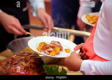 waiter serves roasted meat and baked potatoes at the party or wedding reception Stock Photo