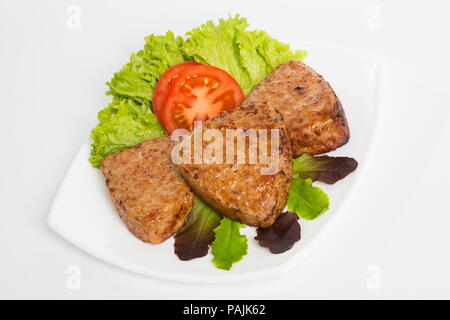 Three fried breaded cutlet with lettuce and tomatoes on white background Stock Photo