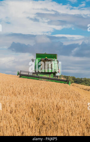 UK Farming, a John Deere Hillmaster combine at work on a winter barley crop, with copy space Stock Photo