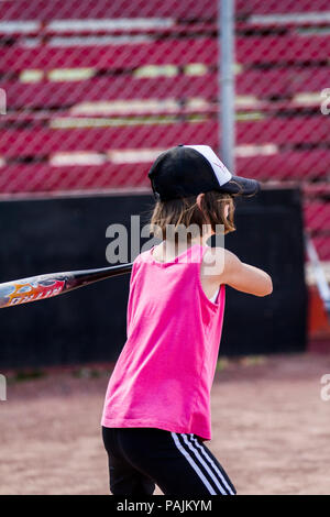 Eight yeqr old girl, in red  tank top and hat, getting ready to swing bat. Model Relese $104 Stock Photo