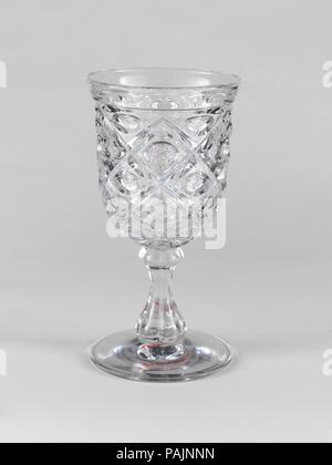 Goblet. Culture: American. Dimensions: H. 6 3/4 in. (17.1 cm); Diam. 3 1/2 in. (8.9 cm). Date: 1850-60.  With the development of new formulas and techniques, glass-pressing technology had improved markedly by the late 1840s. By this time, pressed tablewares were being produced in large matching sets and innumerable forms. During the mid-1850s, colorless glass and simple geometric patterns dominated. Catering to the demand for moderately-priced dining wares, the glass industry in the United States expanded widely, and numerous factories supplied less expensive pressed glassware to the growing m Stock Photo