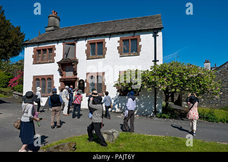 People tourists visitors outside Museum of the Old Grammar School (formerly attended by William Wordsworth) Hawkshead Cumbria England UK Britain Stock Photo