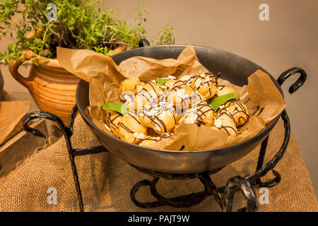 Profiteroles dessert with cream and chocolate glaze on a plate served in restaurant Stock Photo