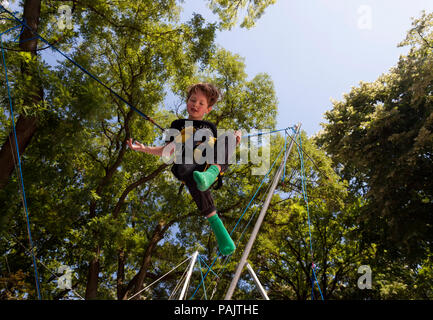Happy young boy (5 years old) jumping on bungee tramplone Stock Photo