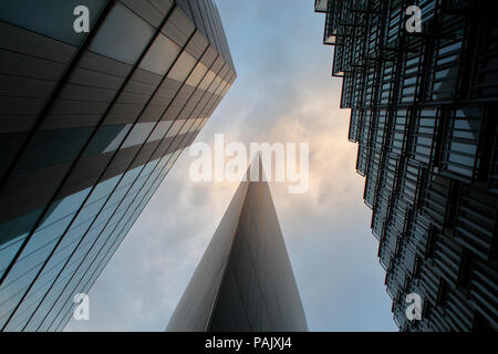 Looking straight up the buildings at More London Place, London Bridge City. just as dawn is breaking in a mainly cloudy sky Stock Photo