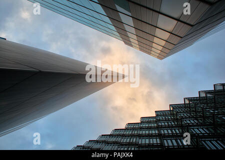 Looking straight up the buildings at More London Place, London Bridge City. just as dawn is breaking in a mainly cloudy sky Stock Photo