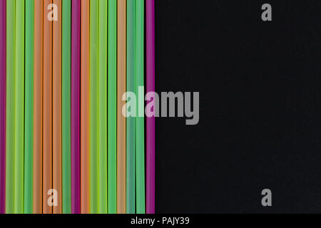 Lined up bright colorful plastic straws decorative art design as bar drink beverage single use product concept isolated on black background Stock Photo