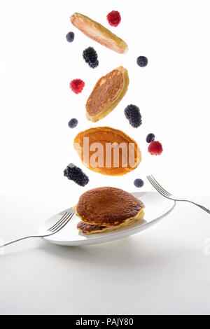 Flying stack of pancakes with blueberry, blackberry and raspberry isolated on white background Stock Photo