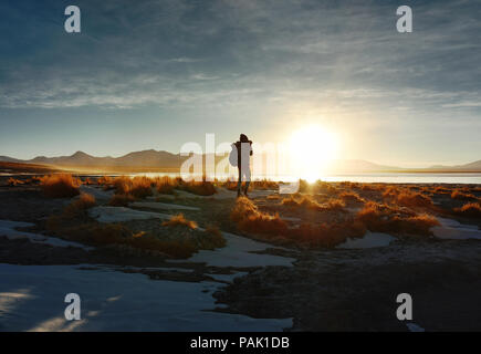 Silhouette of a female photographer capturing the landscape of Termas de Polques in the rising sun. Bolivia, South America Stock Photo