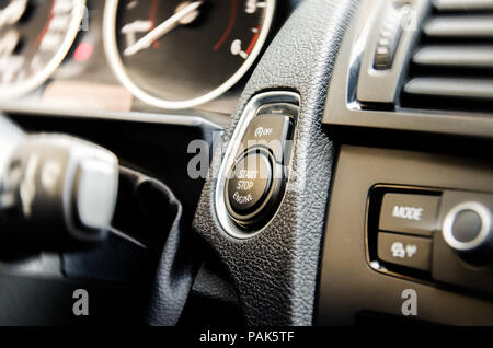 Auto start and stop button on a modern premium car interior suggesting fuel economy, modern technology and eco friendlyness on a bright sunny day with Stock Photo