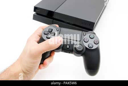 CLUJ-NAPOCA, ROMANIA - 25 FEBRUARY: Illustrative editorial image of Sony Playstation 4 console with Dualshock 4 controller in a man's hand on a white  Stock Photo