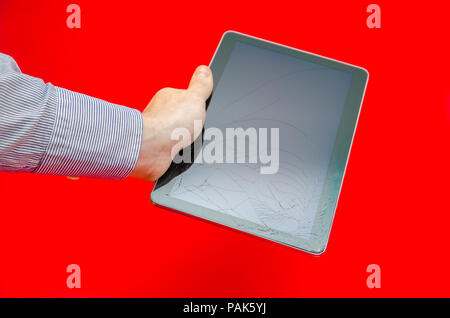 Cracked touch screen display glass in a business man's hand on a red alerted background suggesting fragile electronics and fix and repair on expensive Stock Photo