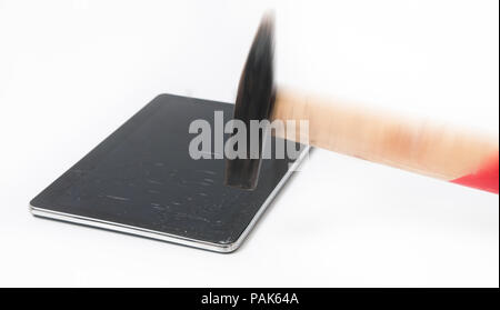 A hammer hitting a broken tablet screen with speed and strength with a motion look on an isolated white background suggesting the need for service and Stock Photo