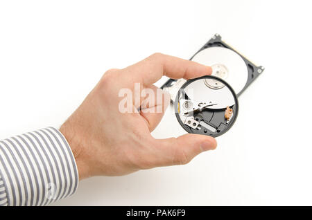 A tech guy inspecting a hard disk through a magnifying glass looking for broken pieces in order to recover files and data Stock Photo
