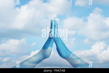 Meditation concept as hands put together in a praying or relaxation pose as a meditative or state of zen idea on a blue sky. Stock Photo