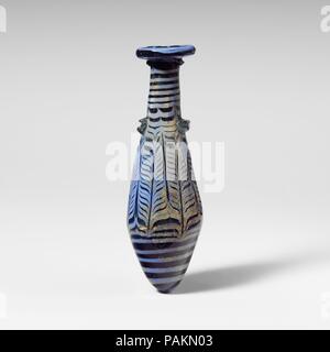 Glass alabastron (perfume bottle). Culture: Greek, Eastern Mediterranean. Dimensions: H.: 5 in. (12.7 cm). Date: 2nd-1st century B.C..  Translucent blue, with handles in light blue green; trail in opaque greyish light blue.  Broad slightly inward-sloping rim-disk with thick rounded edge and radiating tooling marks on lower surface; tall cylindrical neck, expanding downward; straight-sided fusiform body expanding downward, then tapering in to pointed bottom; two horizontal lug handles applied over trail at top of body, one with a deep horizontal indent in surface; one small marvered blob of tra Stock Photo