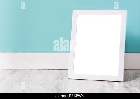 Frame mockup on white wooden floor and turquoise wall. Copyspace. Stock Photo