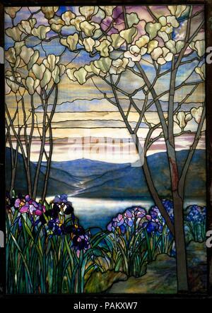 Magnolias and Irises. Culture: American. Designer: Designed by Louis Comfort Tiffany (American, New York 1848-1933 New York). Dimensions: 60 1/4 x 42 in. (153 x 106.7 cm). Maker: Tiffany Studios (1902-32). Date: ca. 1908.  This Tiffany Studios window was designed as a memorial to the Frank family of New York and was originally installed in a mausoleum of a Brooklyn cemetery. The River of Life theme is prevalent in Tiffany landscapes created for memorials. The years between 1900 and 1910 were the height of ecclesiastical window production for Tiffany Studios and figural windows were in high dem Stock Photo