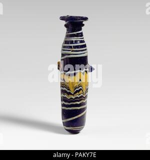 Glass alabastron (perfume bottle). Culture: Greek, Eastern Mediterranean. Dimensions: H.: 4 in. (10.2 cm). Date: late 4th-early 3rd century B.C..  Translucent cobalt blue, with handles in same color; trails in opaque yellow and opaque pale turquoise blue.  Uneven horizontal rim-disk, with radiating tooling marks on upper surface and rough inner edge to mouth; cylindrical, slanting neck; steeply sloping shoulder; slightly bulbous cylindrical body; convex bottom; on body, two lug handles, applied over trail pattern; one with a tooled indent on top, the other flattened into side.  A turquoise blu Stock Photo