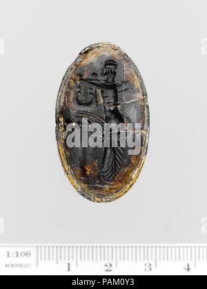 Brown glass oval set in a gilt bronze ring. Culture: Greek. Dimensions: Overall: 9/16 x 3/4 in. (1.4 x 1.9 cm). Date: 3rd-2nd century B.C..  Apollo playing the lyre. Museum: Metropolitan Museum of Art, New York, USA. Stock Photo